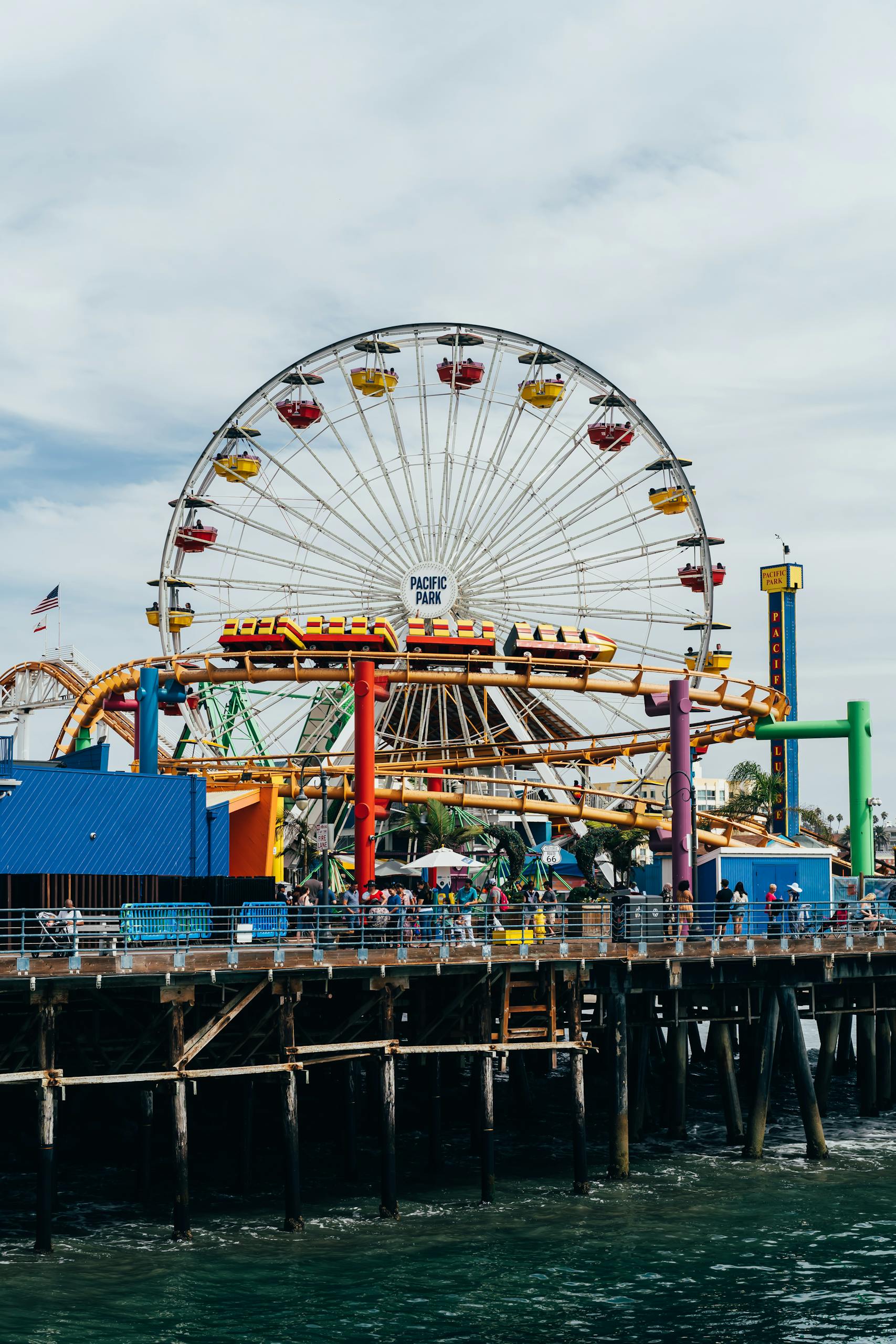 Bright ferris wheel and amusement park rides at Santa Monica Pier, vibrant and fun atmosphere.